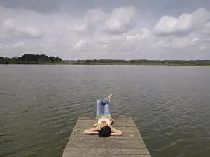 Sole Prints: Woman relaxing lying on a wooden pier at a lake