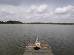 Sole Prints: Woman relaxing lying on a wooden pier at a lake