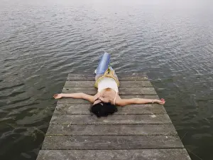 Sole Prints: Woman relaxing lying on a wooden pier at a lake