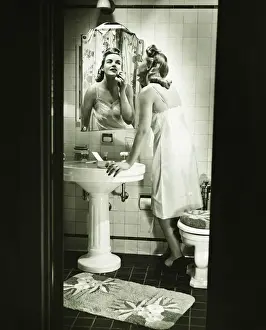Washing Prints: Woman removing make up in front of mirror in bathroom, (B&W)