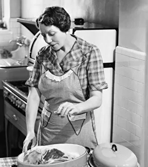 35 39 Years Collection: Woman seasoning meat in roasting dish (B&W)