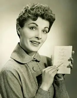 Neat Prints: Woman showing shopping list in studio, (B&W), portrait
