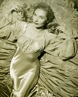 Woman in silk night gown lying on bed, (B&W), overhead view