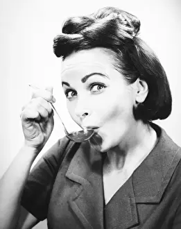 Woman sipping from spoon, (B&W), portrait