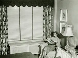 1950s Style Prints: Woman sitting on armchair in bedroom, reading fashion magazine (B&W)