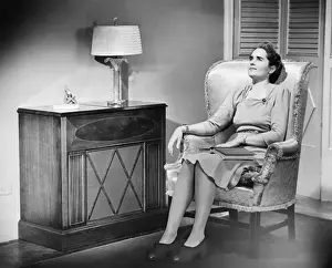 Woman sitting in armchair with book on knees (B&W)