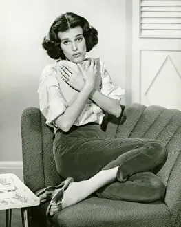 One Mid Adult Woman Only Prints: Woman sitting on couch, cuddling book, (B&W), portrait
