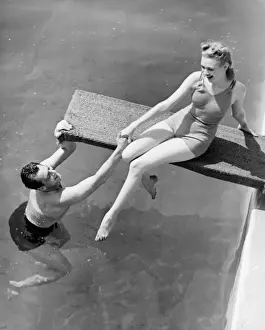 Pulling Prints: Woman sitting on diving board, man grasping her hand (B&W), elevated view