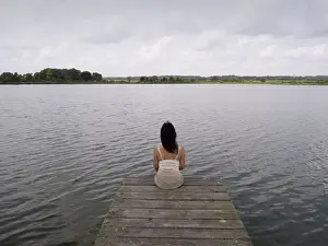 Sole Prints: Woman sitting on a wooden pier at a lake