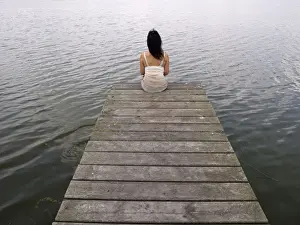 East Prints: Woman sitting on a wooden pier at a lake