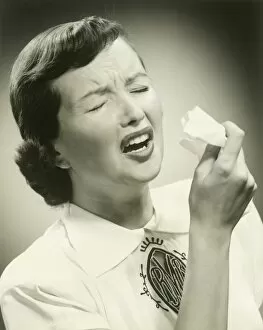 Woman sneezing, studio shot
