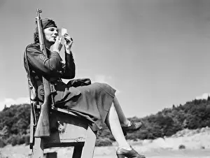 Woman Soldier Sitting and Applying Lipstick to Her Face