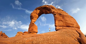 Underneath Gallery: Woman standing under Delicate Arch natural stone arch, Arches-Nationalpark, near Moab, Utah