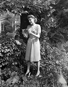 Back Or Front Yard Prints: Woman standing at mailbox, looking at letters, (B&W)