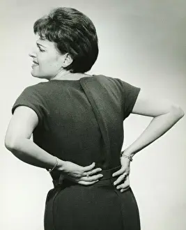 40 49 Years Prints: Woman in studio grasping back in pain, (B&W)