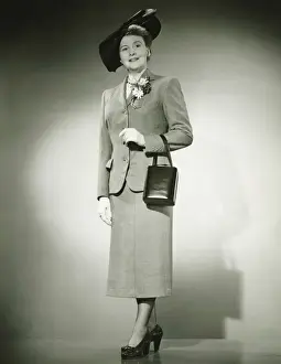 50 59 Years Prints: Woman in suit and fashionable hat standing in studio, (B&W)