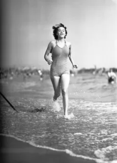 Woman in swimsuit running on shoreline, (B&W)