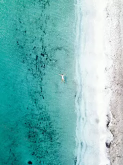 Abstract Aerial Art Prints Gallery: Woman takes a bath and floats in a turquoise sea. Stintino, Sardinia, Italy. Aerial view