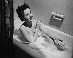 20 25 Years Gallery: Woman taking bubble bath, holding soap bar, (B&W), portrait