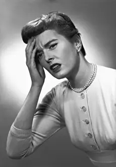 Woman touching forehead in studio, (B&W)