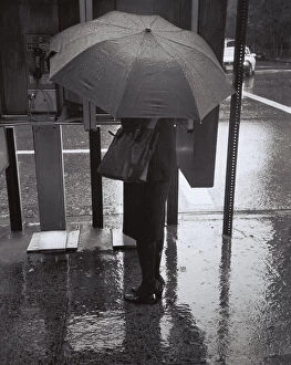Weather Gallery: Woman with umbrella talking on public phone in rain