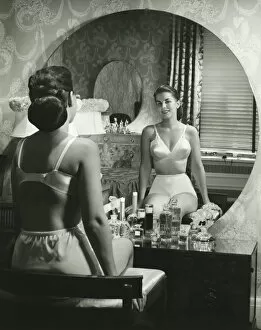 Images Dated 5th May 2006: Woman in underwear sitting in front of vanity table, (B&W), rear view