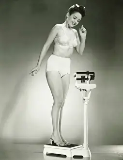 Woman in underwear standing on scale, (B&W)
