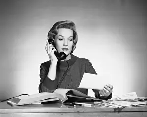 Woman using phone and looking at paper