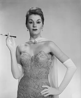 Woman wearing evening dress, holding cigarette, portrait