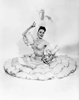 Woman wearing frill dress and headwear, sitting on ground, portrait