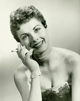 Glove Prints: Woman wearing lace glove holding cigarette in studio, (B&W), portrait