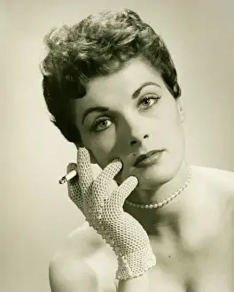 Glove Prints: Woman wearing lace glove holding cigarette in studio, (B&W), portrait