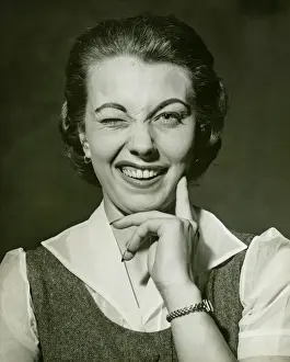 Hand On Chin Prints: Woman winking in studio, (B&W), portrait