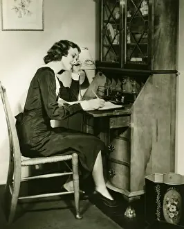 Woman writing letter at bureau, (B&W)
