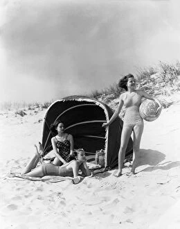 Three Women On Beach Two Are Under Canvas Sun Wind Screen With Fringe Other Is Standing