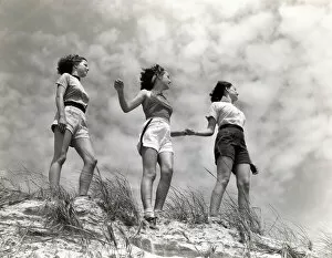 Sand Dune Gallery: Three women standing on beach, holding hands, smiling. (Photo by H