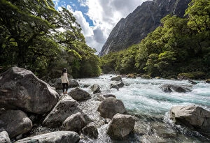 The women stands on a stone in the midst of watercourse with mountains in Milford highway