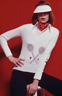 Prints of A woman modelling women's fashions in a studio portrait, wearing a white knitted jumper featuring a motif of two tennis racquets and red tennis balls on the front The Grand Slam Gallery: Women's Fashion