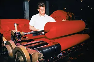Workman Placing Bolts of Cloth on Roller Machine
