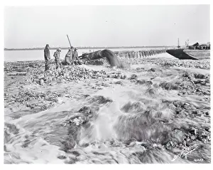 Workmen Pumping Sand From an Inlet