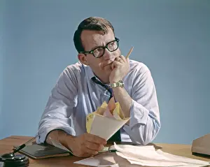 Contemplation Prints: Worried Looking Man With Glasses At Desk Clutching Papers Bills Debt Concern Money Pencil