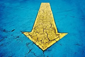 Yellow arrow on blue concrete with cracks