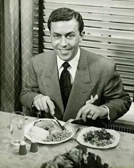 Interior Space Prints: Young businessman eating dinner, (B&W), portrait