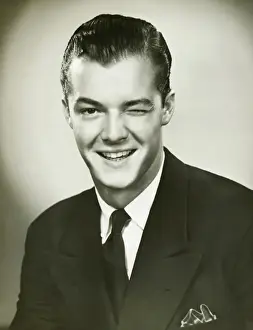 Raised Eyebrow Prints: Young businessman winking, posing in studio, (B&W), portrait