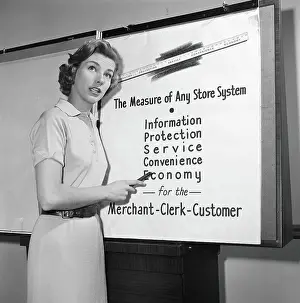 Young career woman giving business presentation, pointing at poster