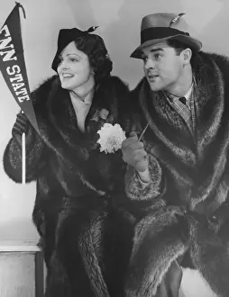 Glove Prints: Young couple in fur coats sitting, facing same direction, (B&W)