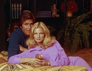 Casual Collection: Young couple leaning on sofa, woman holding glass