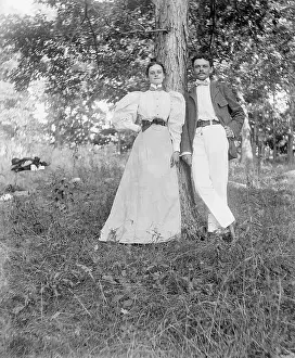 Young Couple Leaning Against Tree