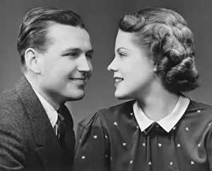Young couple looking in eyes in studio, (B&W), portrait