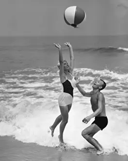Swimming Trunks Prints: Young couple playing with beach ball at waters edge